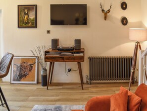 Ein Wohnzimmer mit einem Holztisch, einem Fernseher, einer Heizung und einer Lampe.