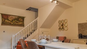 A dining area with a white table, orange chairs, and a staircase with white railings.