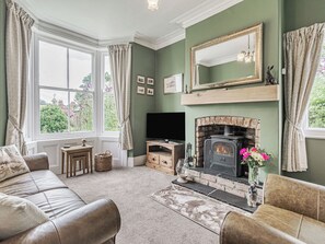 A cozy living room with a fireplace, green walls, and a comfortable sofa.