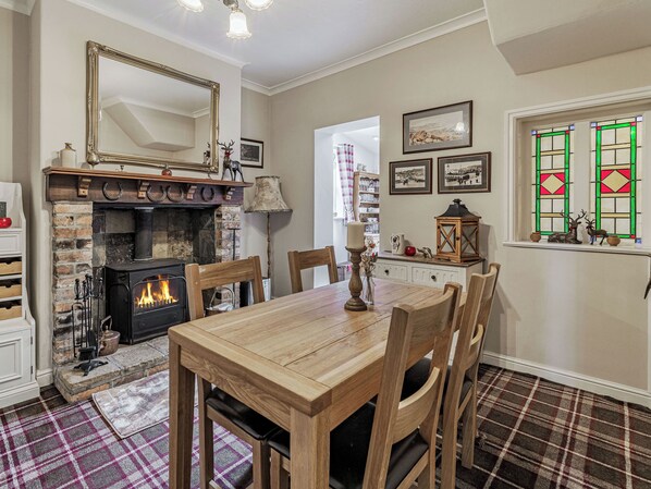 A cozy dining area with a fireplace, wooden table, and chairs.