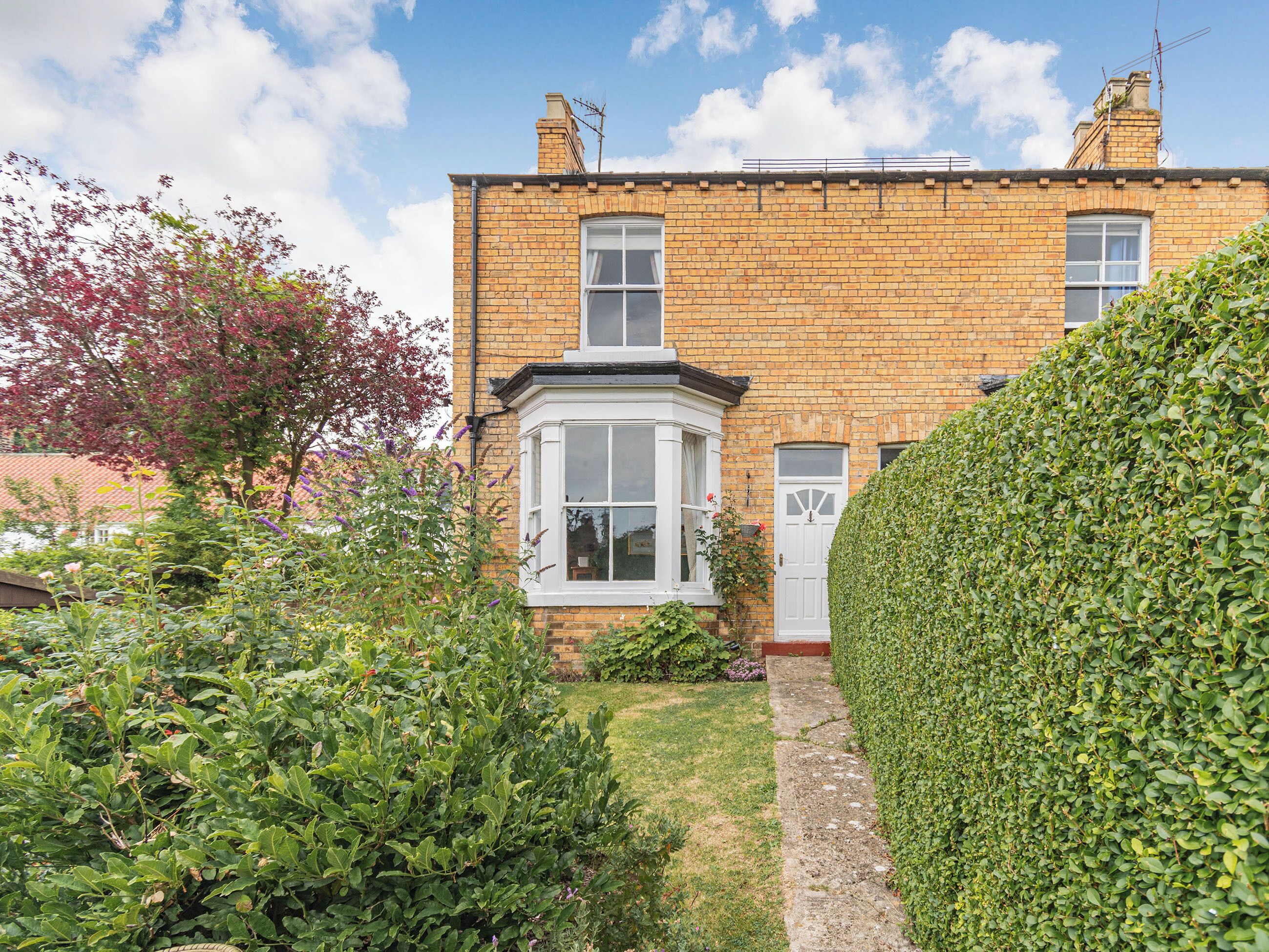 A brick house with a bay window and a white door.