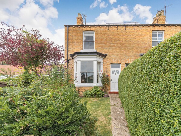 A brick house with a bay window and a white door.