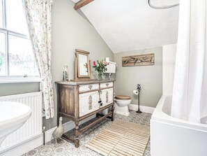 A bathroom with a wooden vanity, a toilet, and a bathtub.