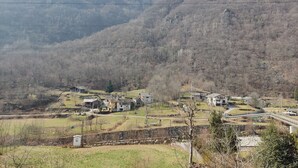 Un paysage rural avec des maisons, un mur de pierre et un pont.