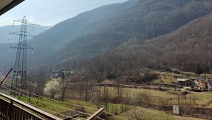 Une vue sur un paysage montagneux, avec une pylône de ligne électrique et un petit village en contrebas.