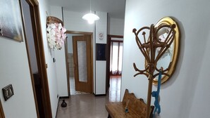 Un couloir avec un banc en bois, un porte-manteau fixé au mur et un luminaire au plafond.