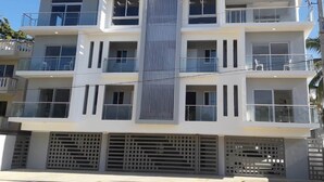 A multi-story building with balconies, large windows, and a central vertical feature. - Your ideal vacation home in Sosua! (Sosúa)