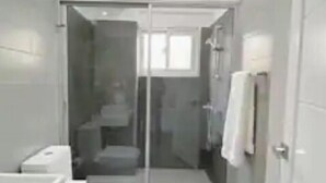 A modern bathroom with a glass shower enclosure, a toilet, and a sink. - Your ideal vacation home in Sosua! (Sosúa)