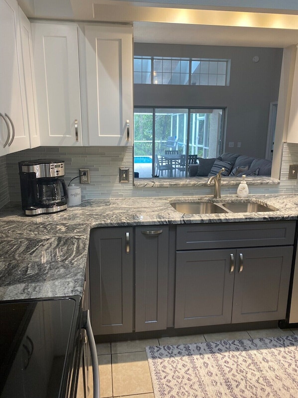 Enjoy a well-lit kitchen with a coffee maker and a large window overlooking the outdoor seating area.