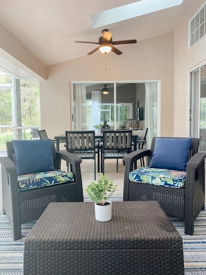 Relax in this serene outdoor seating area with a ceiling fan overhead, a dining table, and a potted plant.