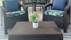 Eine Terrasss mit Korbmöbeln, einem Deckenventilator und einem Blumentopf.