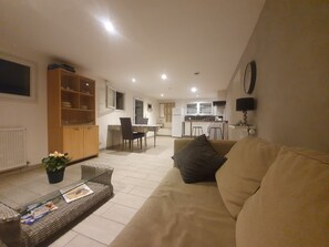 A living room with a sofa, a coffee table, and a dining area with a table and chairs.