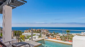 Ein Poolbereich mit Blick auf den Ozean, Liegestühlen und einer Pergola.