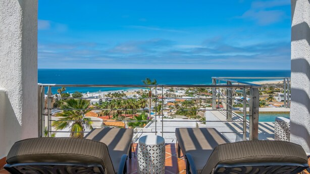 Ein Balkon mit zwei Stühlen und einem Tisch mit Blick auf einen Strand und ein Resort.