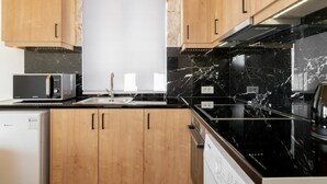 A modern kitchen with wooden cabinets, a black countertop, a microwave, a sink, and a stove.