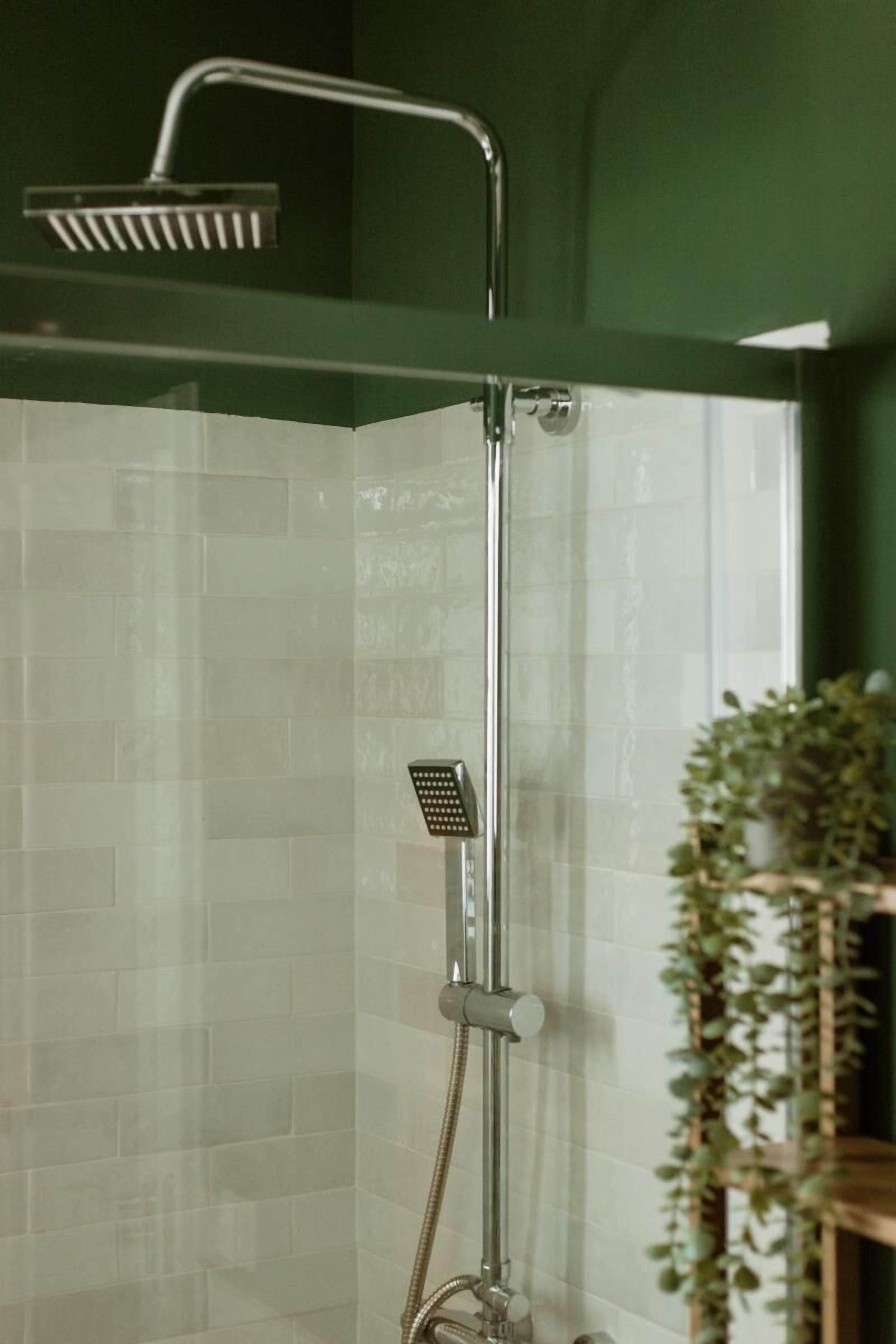 Een douche met een handdouche en een kraan op de muur.