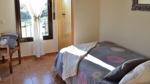 A bedroom with a bed, a chair, a window with curtains, and a door.