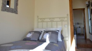A bedroom with a bed, a mirror, and a door leading to another room.