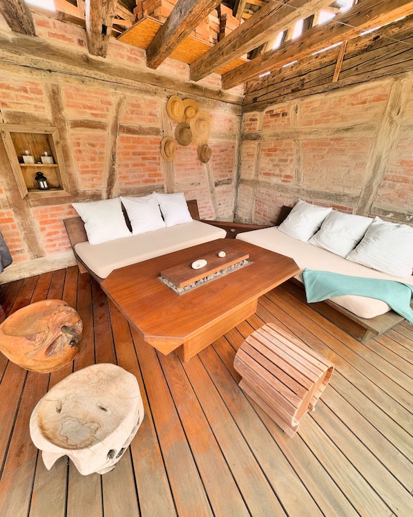 A rustic room with exposed brick walls, wooden beams, a bed with white bedding, a wooden table, and a woven basket. - Gîte Le Chut - Jacuzzi & Swimming pool - 22km Strasbourg (Rangen)
