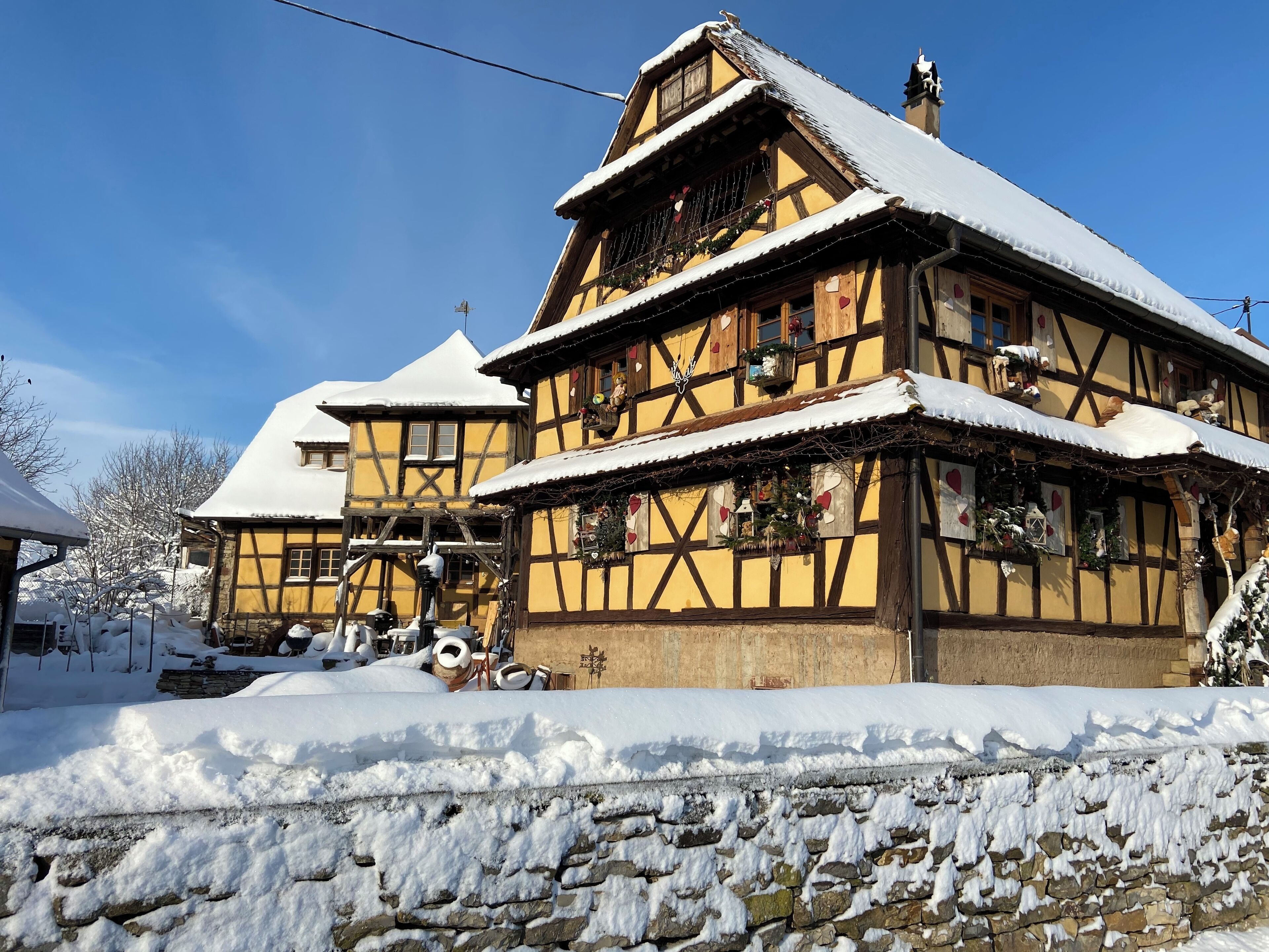 A traditional half-timbered house with a steeply pitched roof, surrounded by snow.