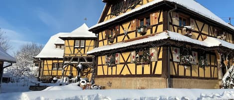 Una casa tradicional con entramado de madera y techo empinado, rodeada de nieve.