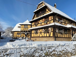 A traditional half-timbered house with a steeply pitched roof, surrounded by snow.