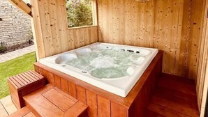 A wooden hot tub with steps leading up to it, surrounded by wooden walls and a stone wall in the background. - Gîte Le Chut - Jacuzzi & Swimming pool - 22km Strasbourg (Rangen)