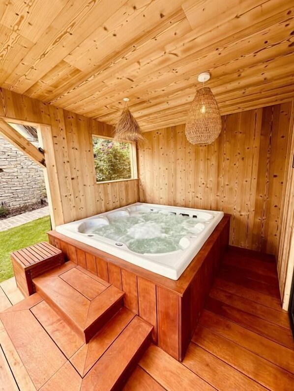 A wooden hot tub with steps leading up to it, surrounded by wooden walls and a stone wall in the background. - Gîte Le Chut - Jacuzzi & Swimming pool - 22km Strasbourg (Rangen)