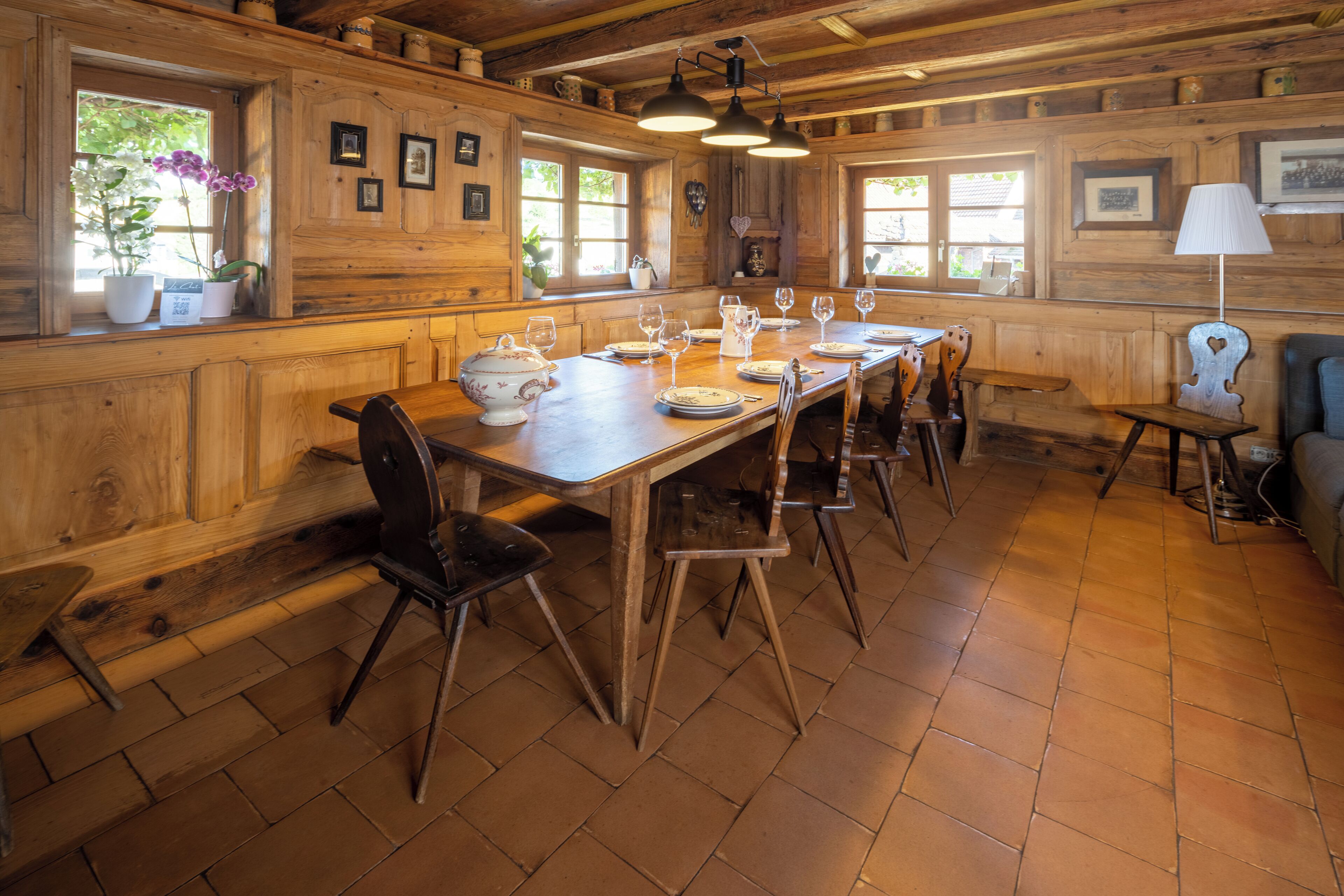 A wooden interior with a long dining table set for six, surrounded by chairs.