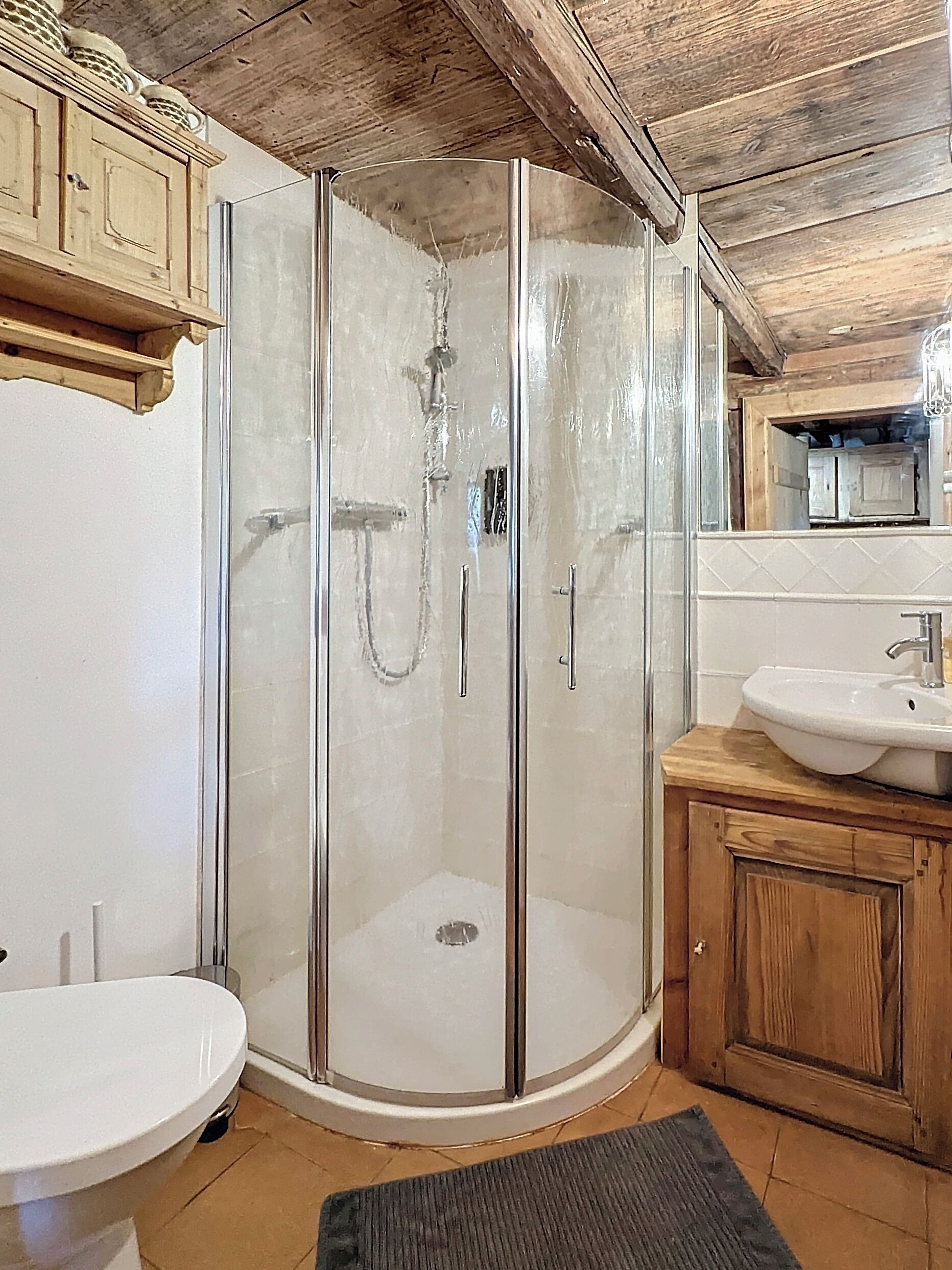 A modern bathroom with a glass-enclosed shower, a wooden vanity with a sink, and a mirror above the vanity.