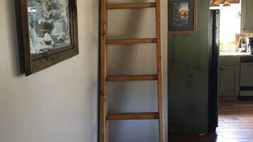 A wooden ladder against a wall with a framed picture.