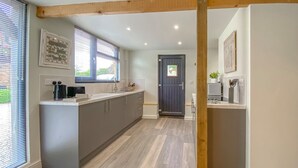 Una cocina moderna con una isla central, vigas de madera y una puerta oscura.