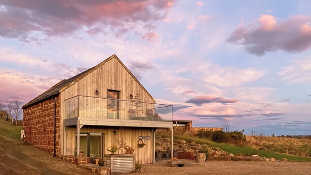 A rustic barn-style building with a large porch and a glass enclosure, surrounded by a rural landscape. - 2 bedroom accommodation in Fettercairn (Fettercairn)