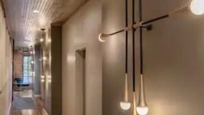Um corredor com soalho de madeira, um tapete estampado em azul e uma moderna luminária pendente.