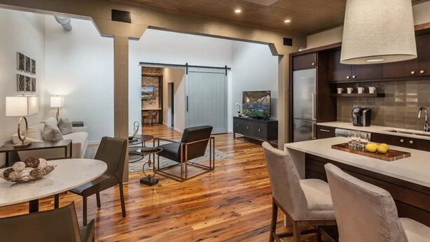 Uma cozinha moderna com uma ilha central, piso de madeira e área de refeições com uma mesa redonda e cadeiras.