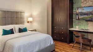 Quarto moderno com cama grande, escrivaninha e vista para o horizonte urbano pela janela.