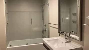 Een bad/douchecombinatie, een haardroger, handdoeken, zeep