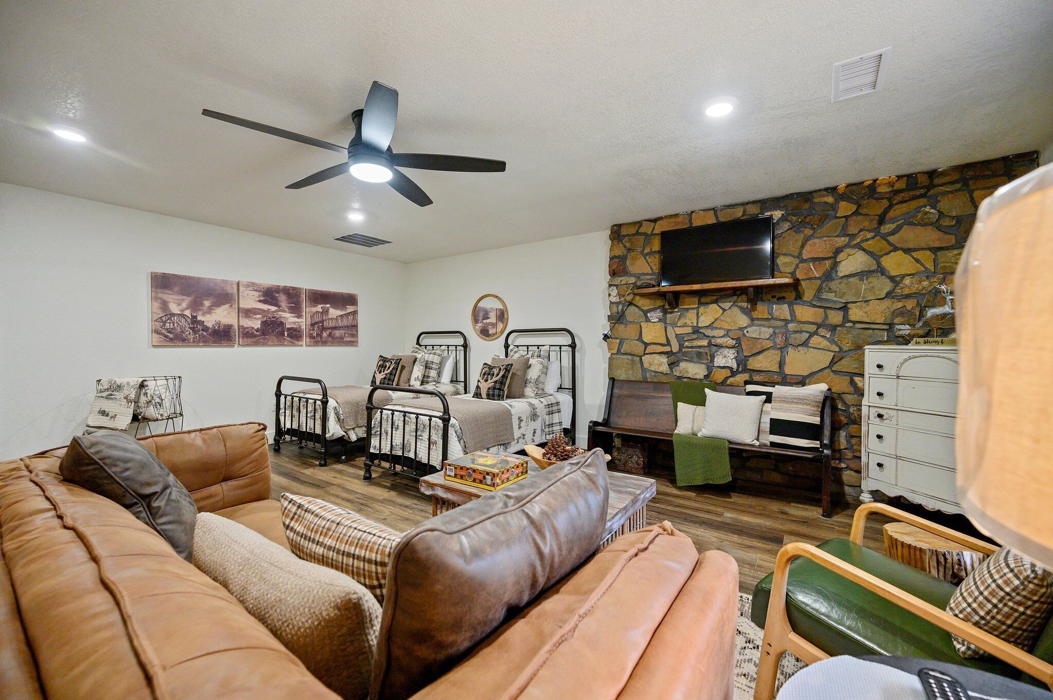 A cozy living room with a brown leather sofa, a green armchair, and a stone fireplace.