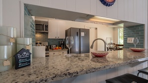 Una cocina moderna con encimeras de granito, electrodomésticos de acero inoxidable y un salpicadero de azulejos azules.