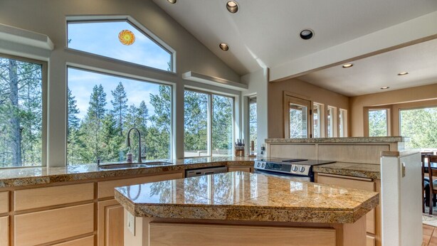 A spacious kitchen with large windows, granite countertops, and wooden cabinets. - Modern Sunriver Luxury Home with Fenced Turf Pet Yard, Large Kids Room, SHARC !! (Sunriver)