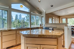 Una cocina amplia con ventanas grandes, encimeras de granito y armarios de madera.