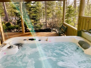 A hot tub on a wooden deck with a bench and a view of a forested area. - Modern Sunriver Luxury Home with Fenced Turf Pet Yard, Large Kids Room, SHARC !! (Sunriver)