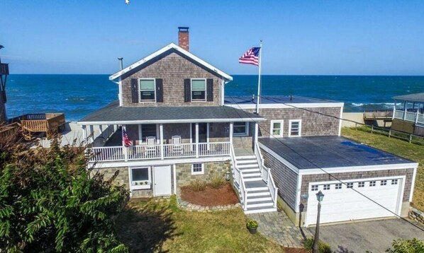A two-story house with a balcony, a garage, and a view of the ocean.