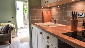 A modern kitchen with a wooden countertop, white cabinets, and a built-in oven. - The Hen House - UK38436 (Bridlington)