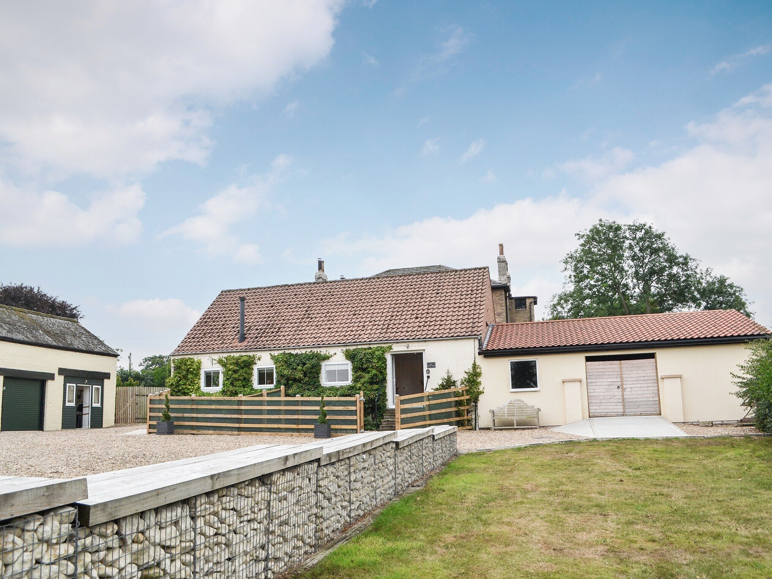 A two-story house with a tiled roof, a stone wall, and a grassy yard.