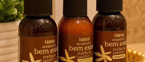 Three bottles of Harus Momento bem estar shampoo on a countertop with a plant and a white box in the background.