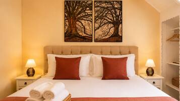 Une chambre d’hôtel avec un grand lit, deux tables de chevet, un tableau accroché au mur et un panier rempli de serviettes.