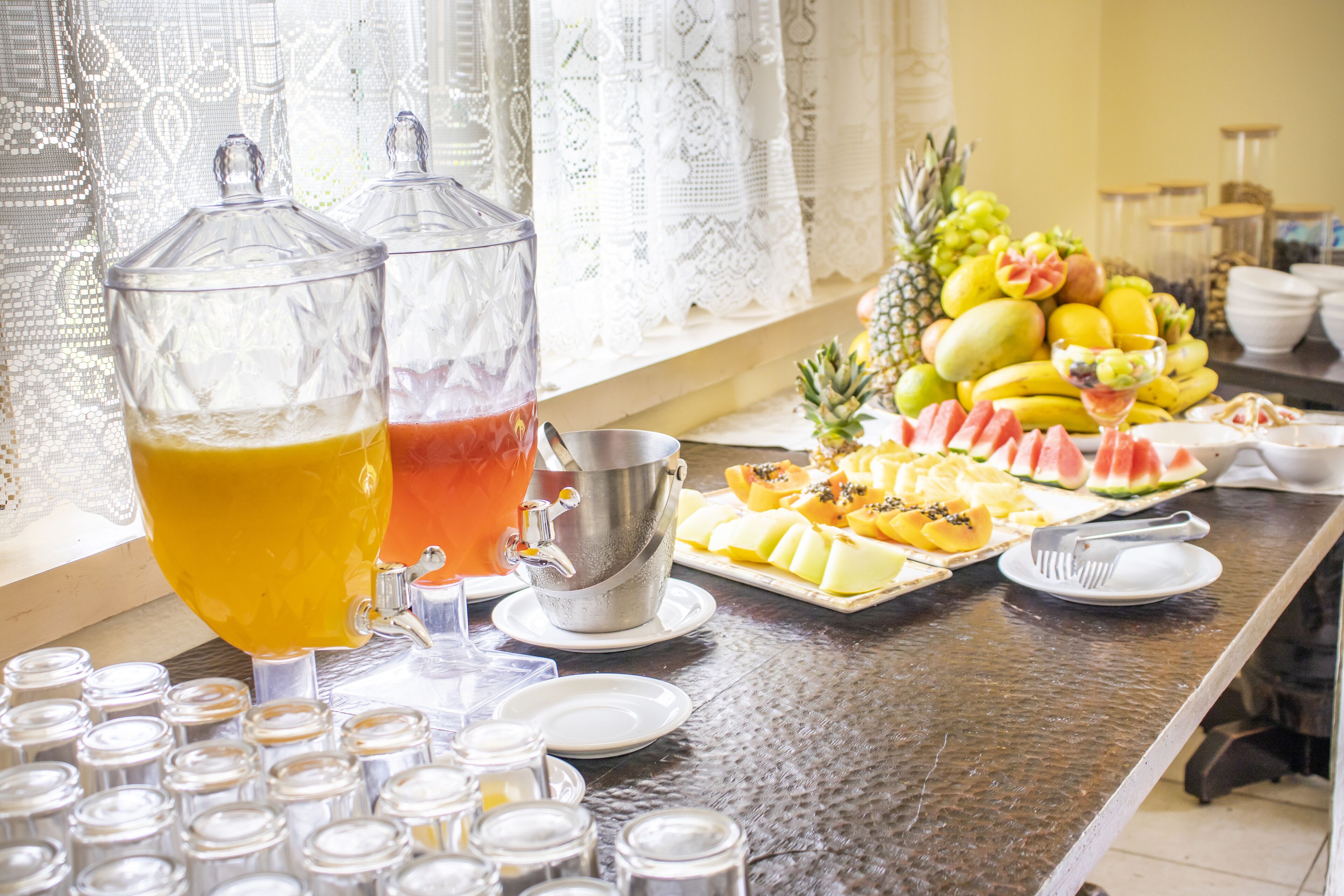 Une table de buffet avec divers fruits, un punch aux fruits et un grand récipient pour servir le punch.