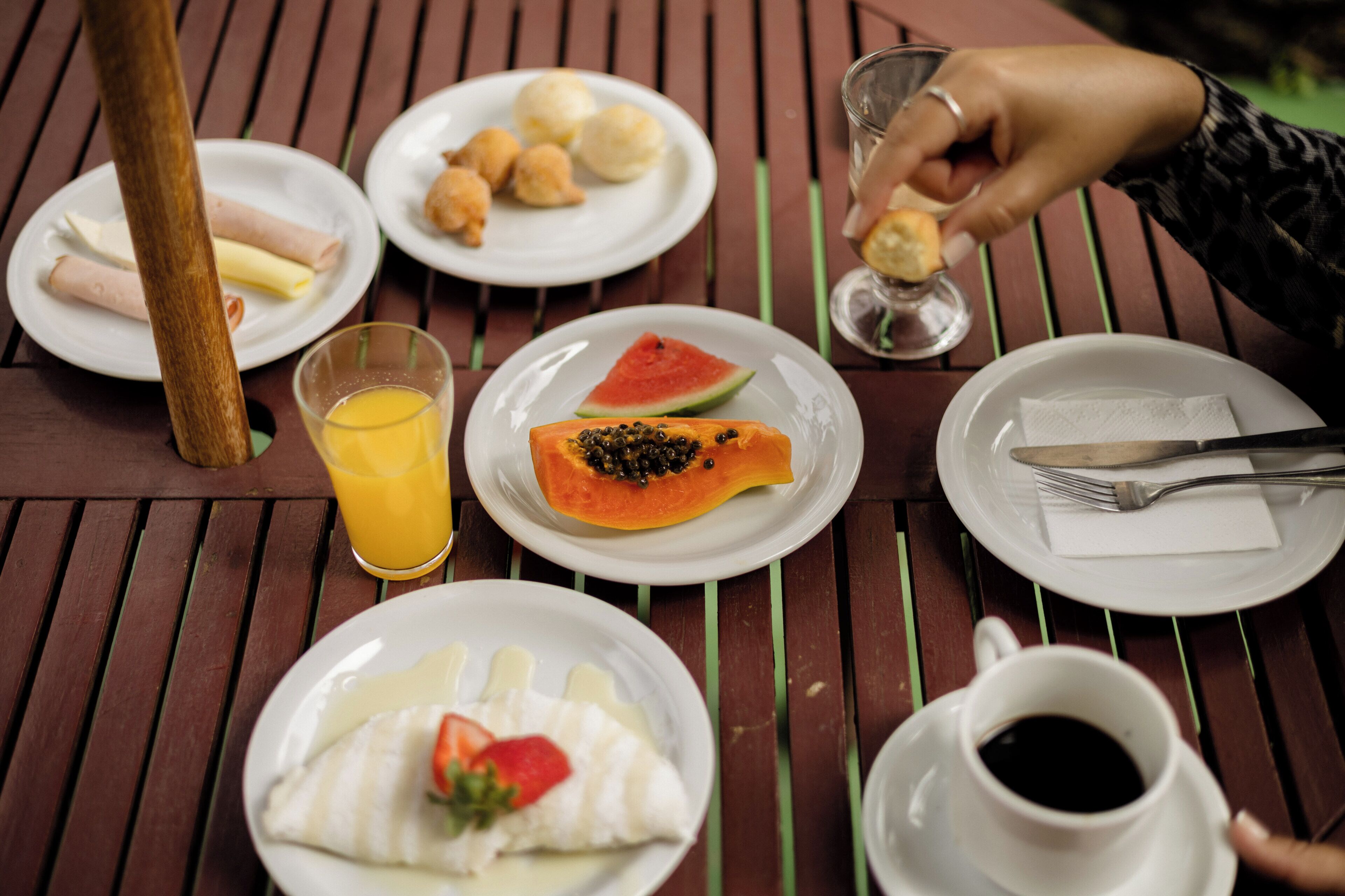 A wooden table with plates of food, a glass of orange juice, a cup of coffee, and a fork and knife.