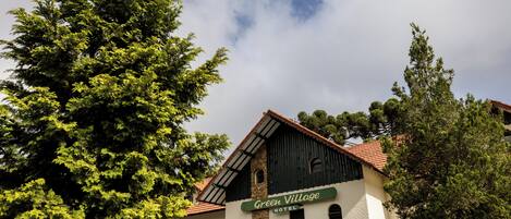A building with a sign reading 'Green Village Hotel' and a stone facade.